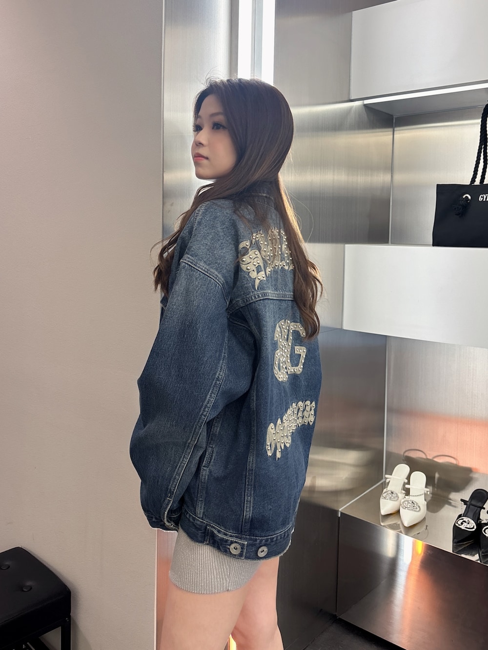 ブラック系のブーツ、シルバー系のワンピース、ブルー系のデニムジャケットを着用したレディースの春コーディネートの5枚目の写真