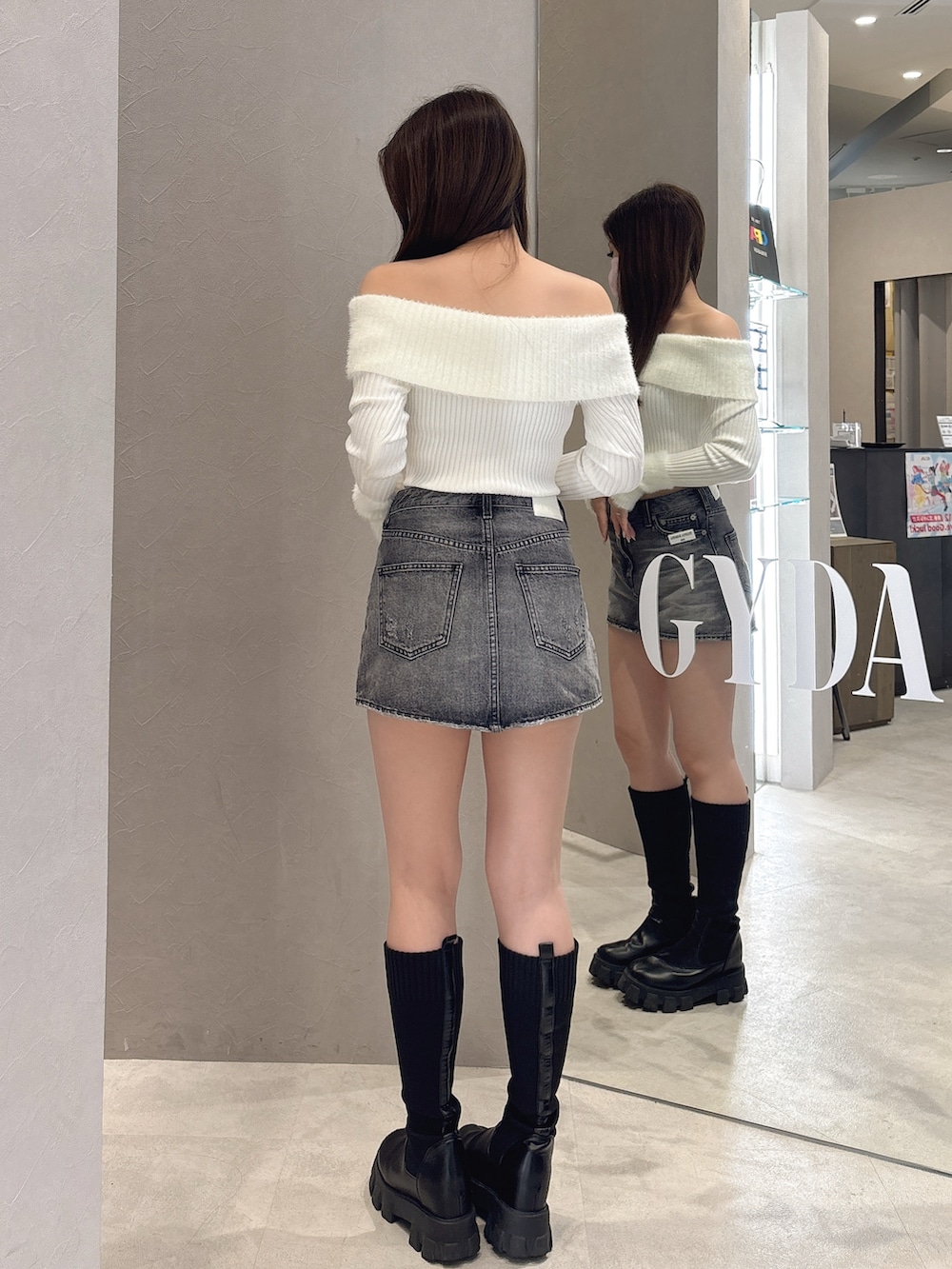 ホワイト系のニット/セーター、ブルー系のデニムスカート、ブラック系のブーツを着用したレディースの秋コーディネートの3枚目の写真