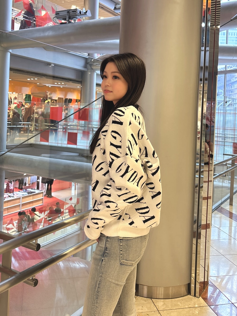 ブラック系のニット/セーター、ブルー系のデニムパンツ、ブラック系のブーツを着用したレディースの春コーディネートの5枚目の写真