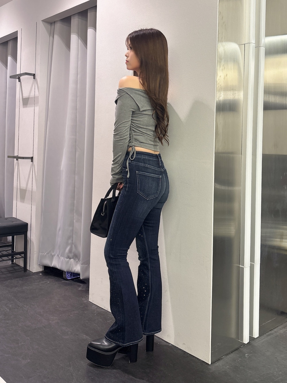 グレー系のTシャツ/カットソー、ブルー系のデニムパンツ、ブラック系のハンドバッグを着用したレディースの秋コーディネートの2枚目の写真