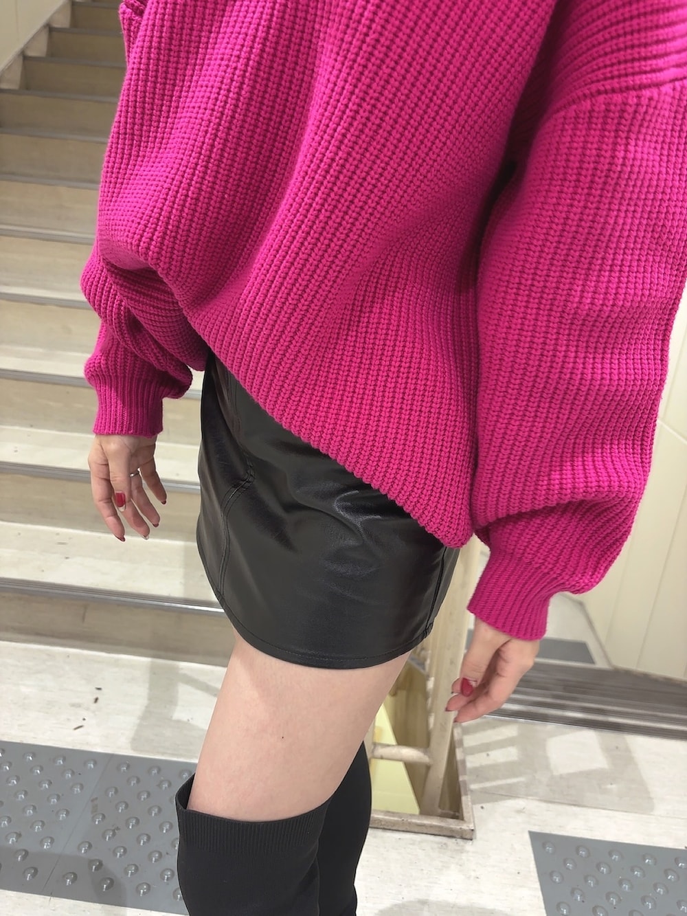 ピンク系のニット/セーター、ブラック系のスカート、ブラック系のブーツを着用したレディースの秋コーディネートの5枚目の写真