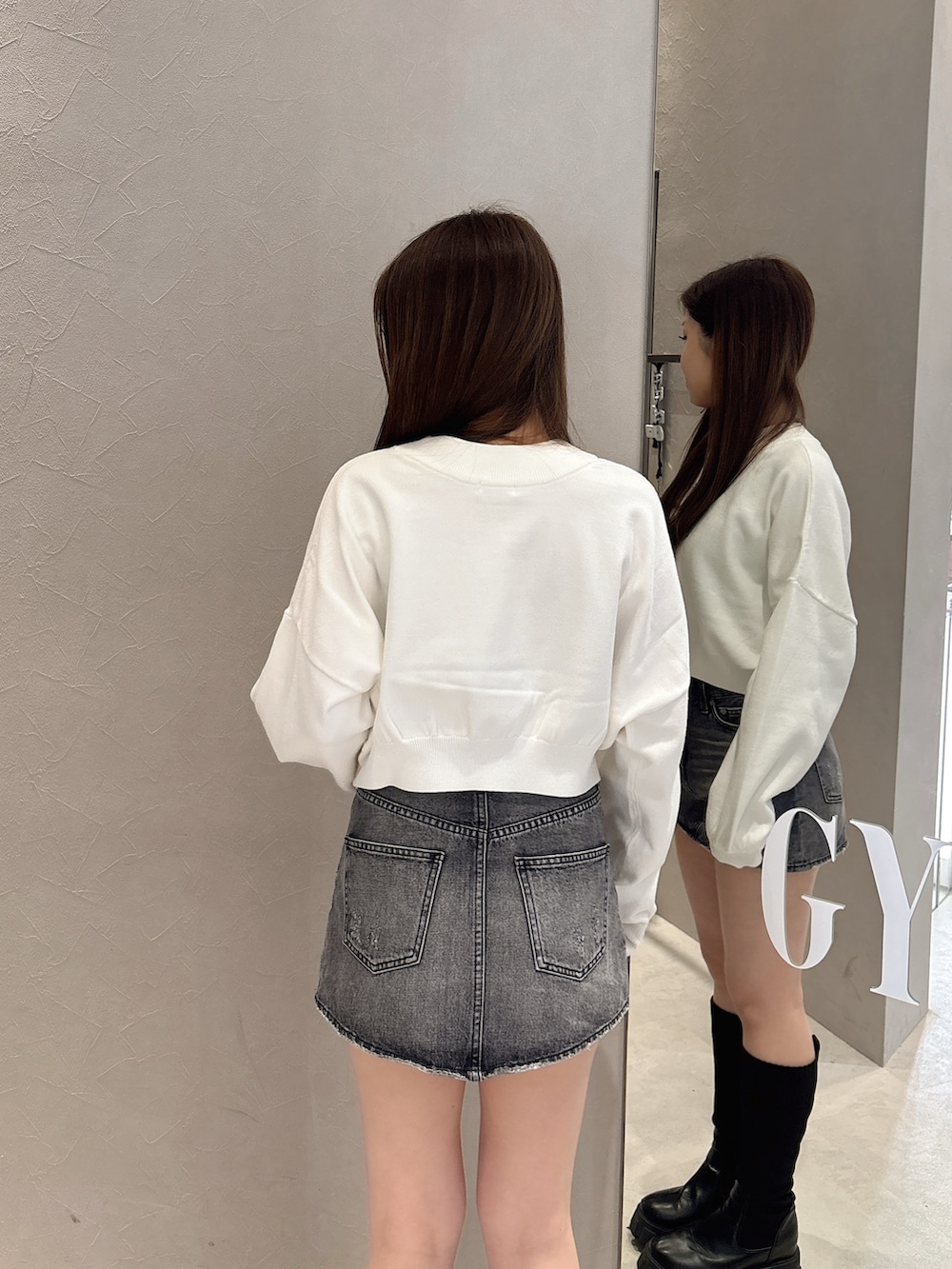 ホワイト系のニット/セーター、ブルー系のデニムスカート、ブラック系のブーツを着用したレディースの秋コーディネートの5枚目の写真