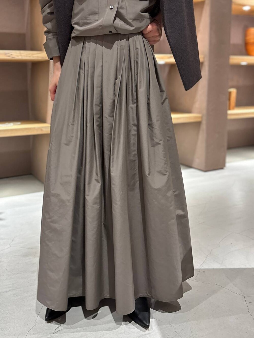 グレー系のニット/セーター、ブラウン系のシャツ/ブラウス、ブラウン系のスカートを着用したレディースの秋コーディネートの7枚目の写真