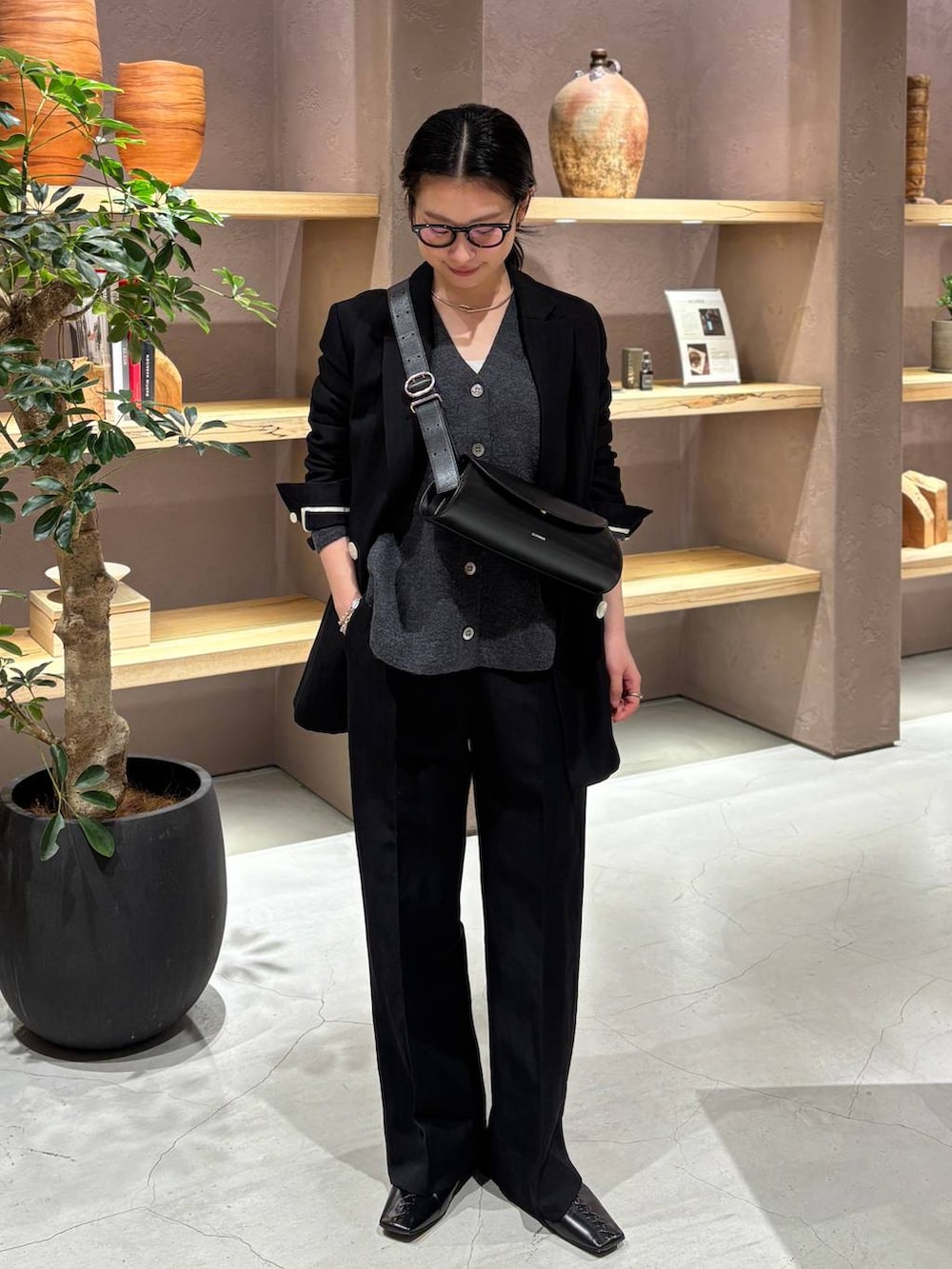 ブラック系のスラックス、ブラック系のテーラードジャケット、グレー系のカーディガン/ボレロを着用したレディースの冬コーディネートの2枚目の写真