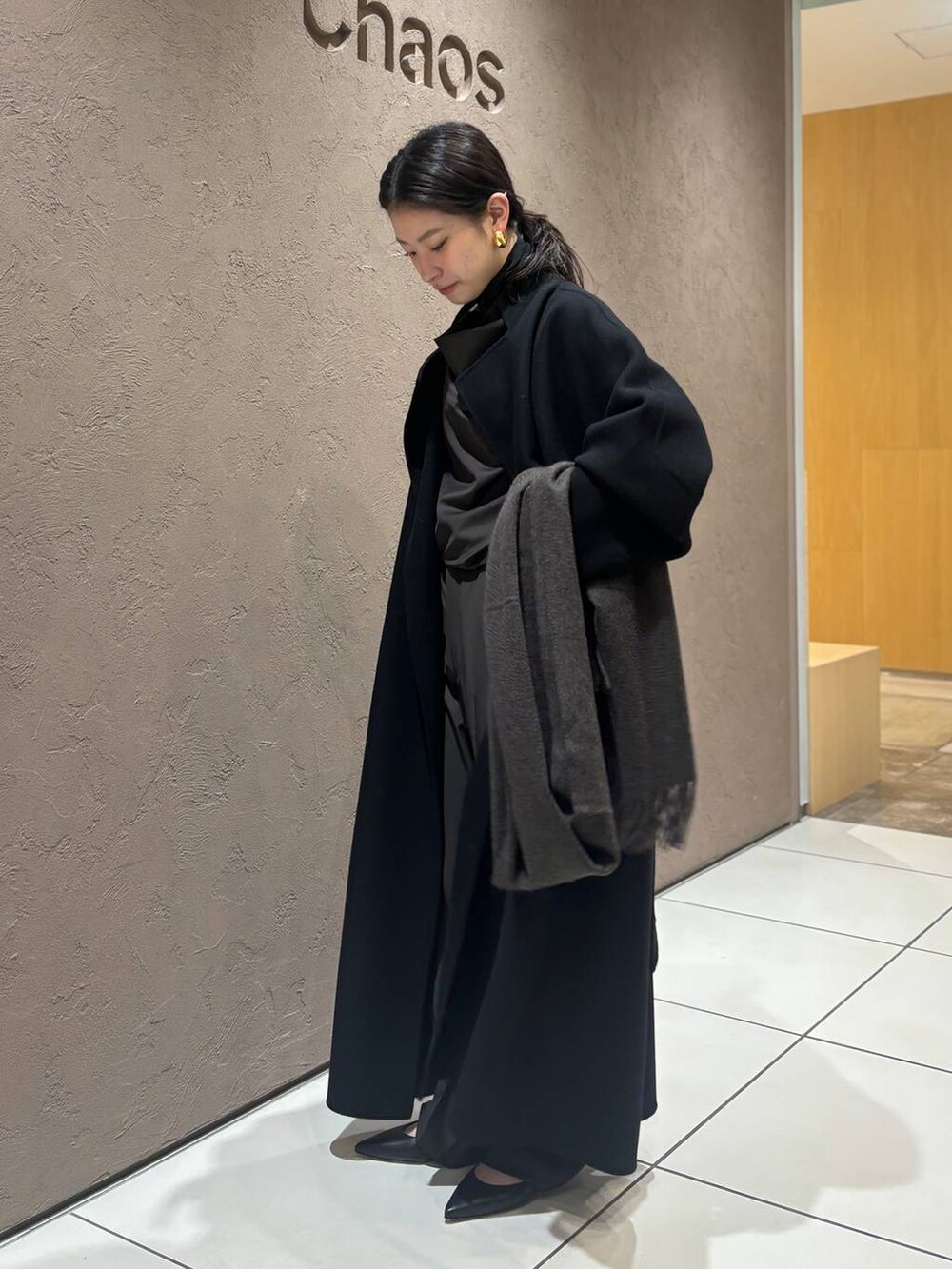 ブラウン系のスラックス、ブラウン系のシャツ/ブラウス、ブラック系のチェスターコートを着用したレディースの秋コーディネートの3枚目の写真