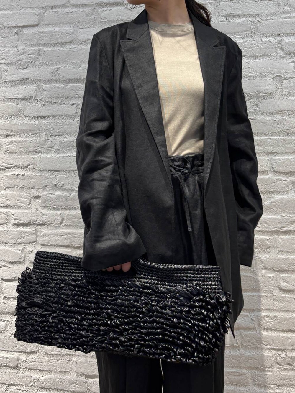 ブラック系のスラックス、ブラック系のテーラードジャケット、ブラウン系のTシャツ/カットソーを着用したレディースの春コーディネートの5枚目の写真