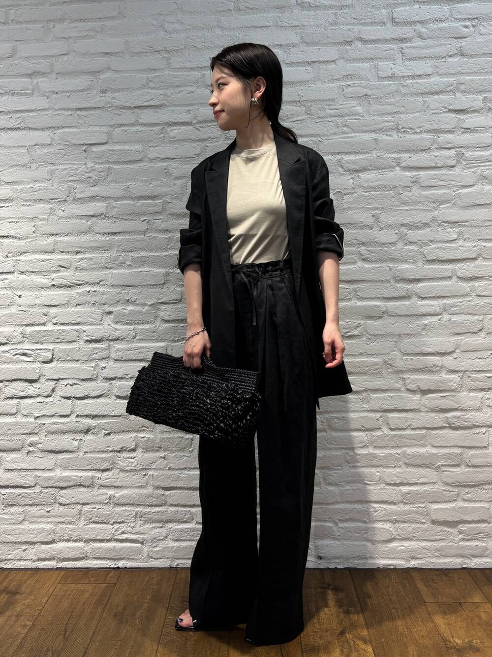 ブラック系のスラックス、ブラック系のテーラードジャケット、ブラウン系のTシャツ/カットソーを着用したレディースの春コーディネートの2枚目の写真