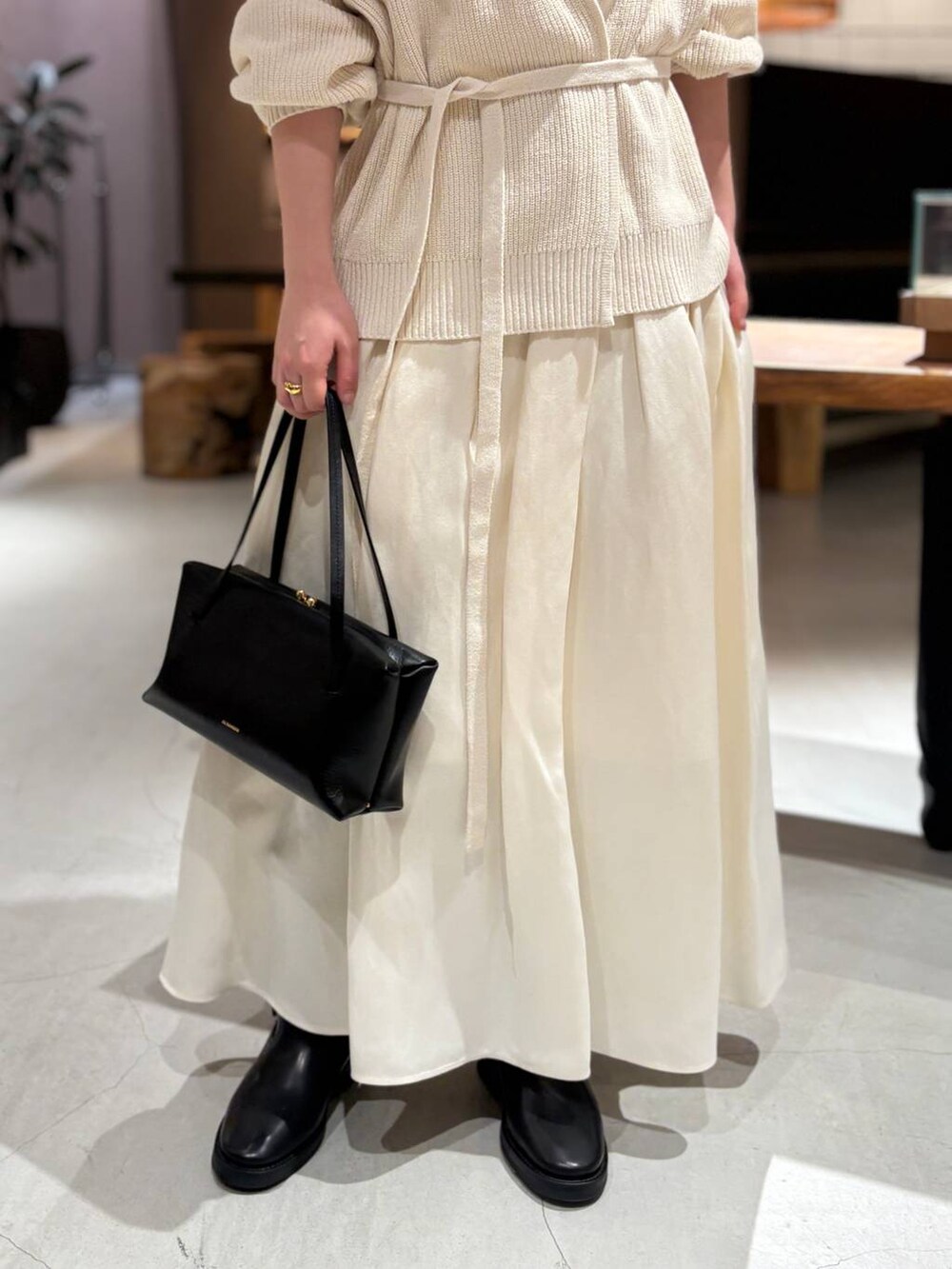 ホワイト系のカーディガン/ボレロ、ホワイト系のタンクトップ、ホワイト系のスカートを着用したレディースの冬コーディネートの6枚目の写真