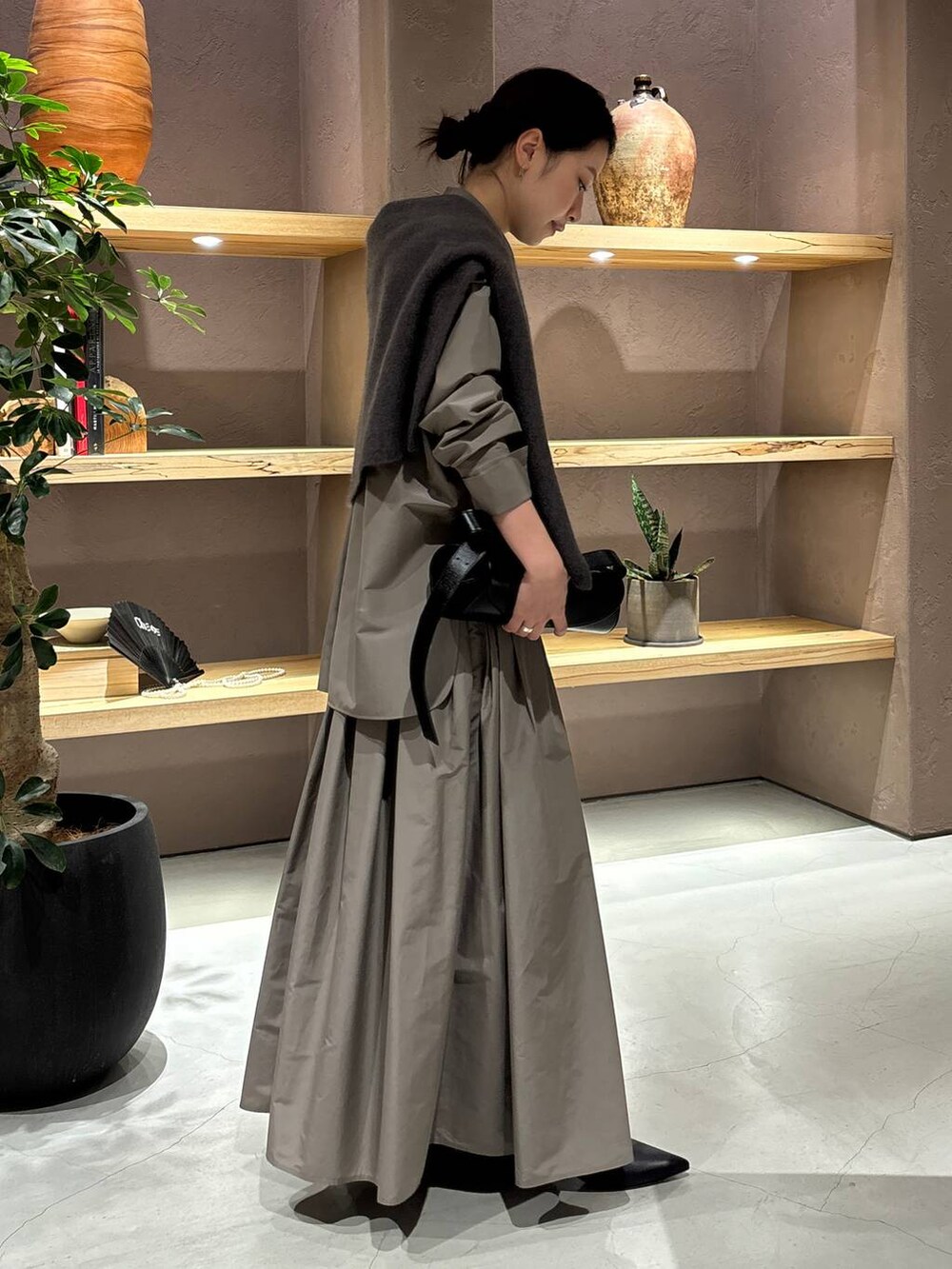 グレー系のニット/セーター、ブラウン系のシャツ/ブラウス、ブラウン系のスカートを着用したレディースの秋コーディネートの2枚目の写真