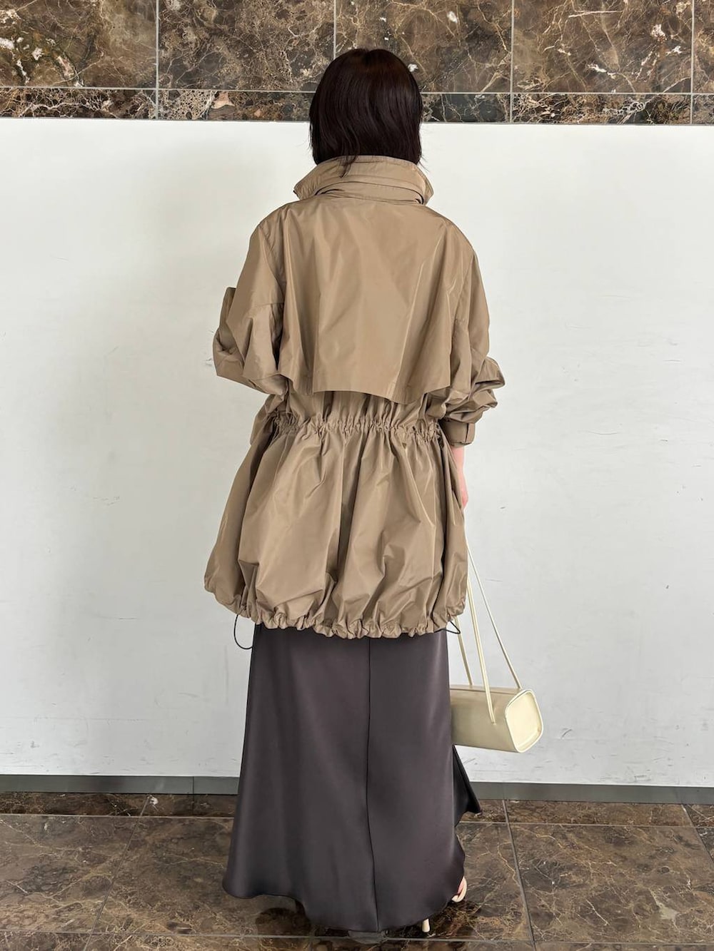 ホワイト系のニット/セーター、ブラウン系のスカート、ベージュ系のブルゾンを着用したレディースの夏コーディネートの4枚目の写真