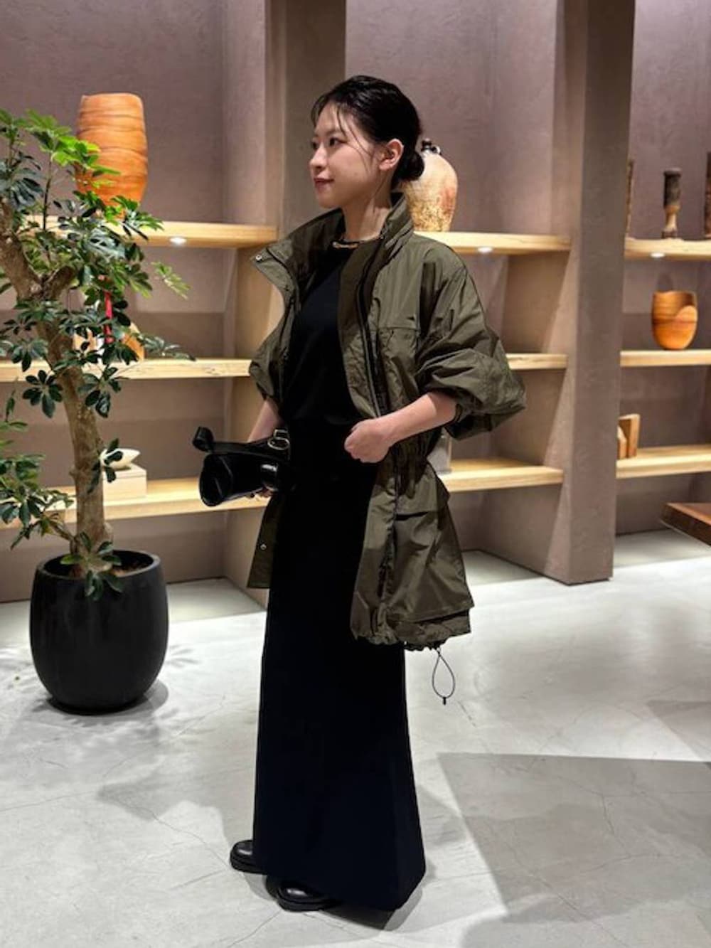 ブラック系のニット/セーター、グリーン系のブルゾン、ブラック系のスカートを着用したレディースの秋コーディネートの3枚目の写真