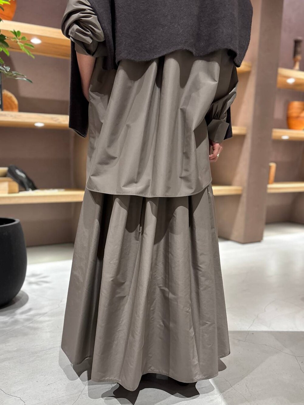 グレー系のニット/セーター、ブラウン系のシャツ/ブラウス、ブラウン系のスカートを着用したレディースの秋コーディネートの9枚目の写真