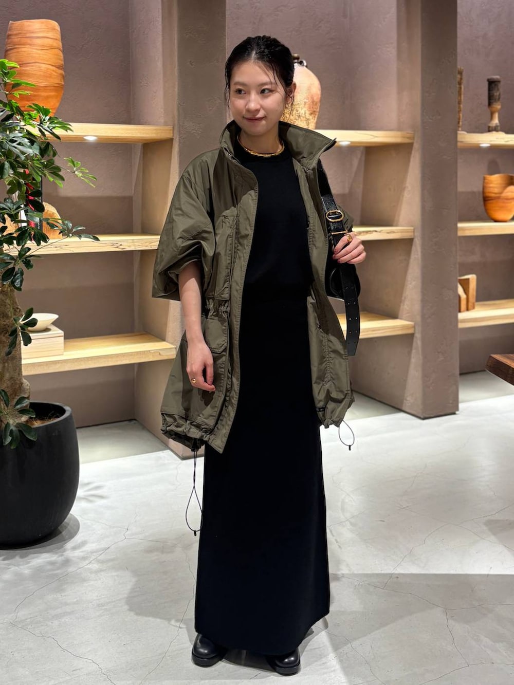 ブラック系のニット/セーター、グリーン系のブルゾン、ブラック系のスカートを着用したレディースの秋コーディネートの2枚目の写真