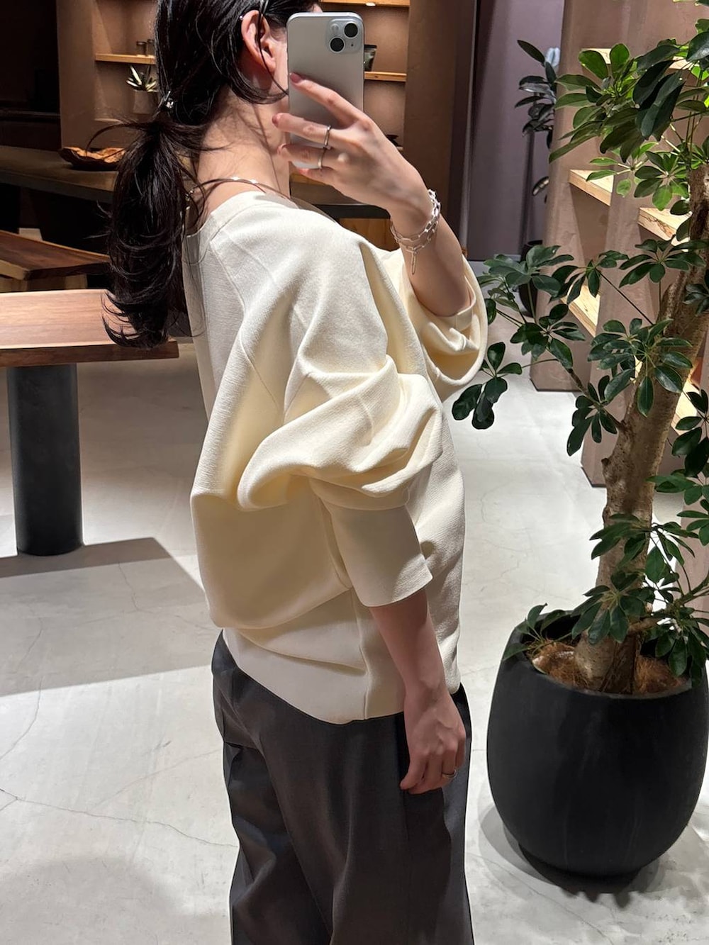 グレー系のスラックス、ホワイト系のカーディガン/ボレロ、ブラック系のトレンチコートを着用したレディースの冬コーディネートの7枚目の写真