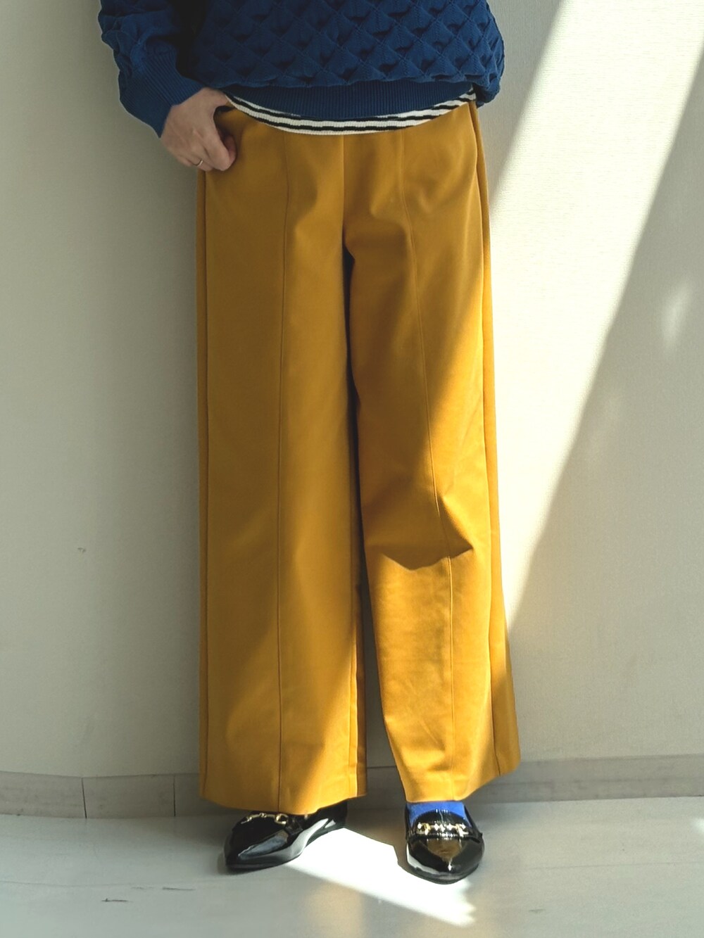 ブルー系のニット/セーター、イエロー系のパンツを着用したレディースの秋コーディネートの3枚目の写真