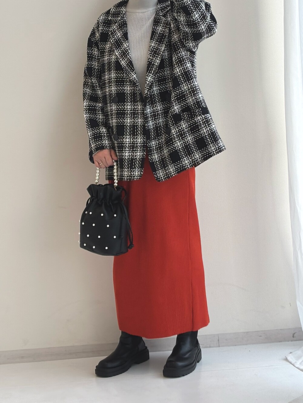 グレー系のニット/セーター、オレンジ系のスカート、ブラック系のジャケット/アウターを着用したレディースの秋コーディネートの2枚目の写真