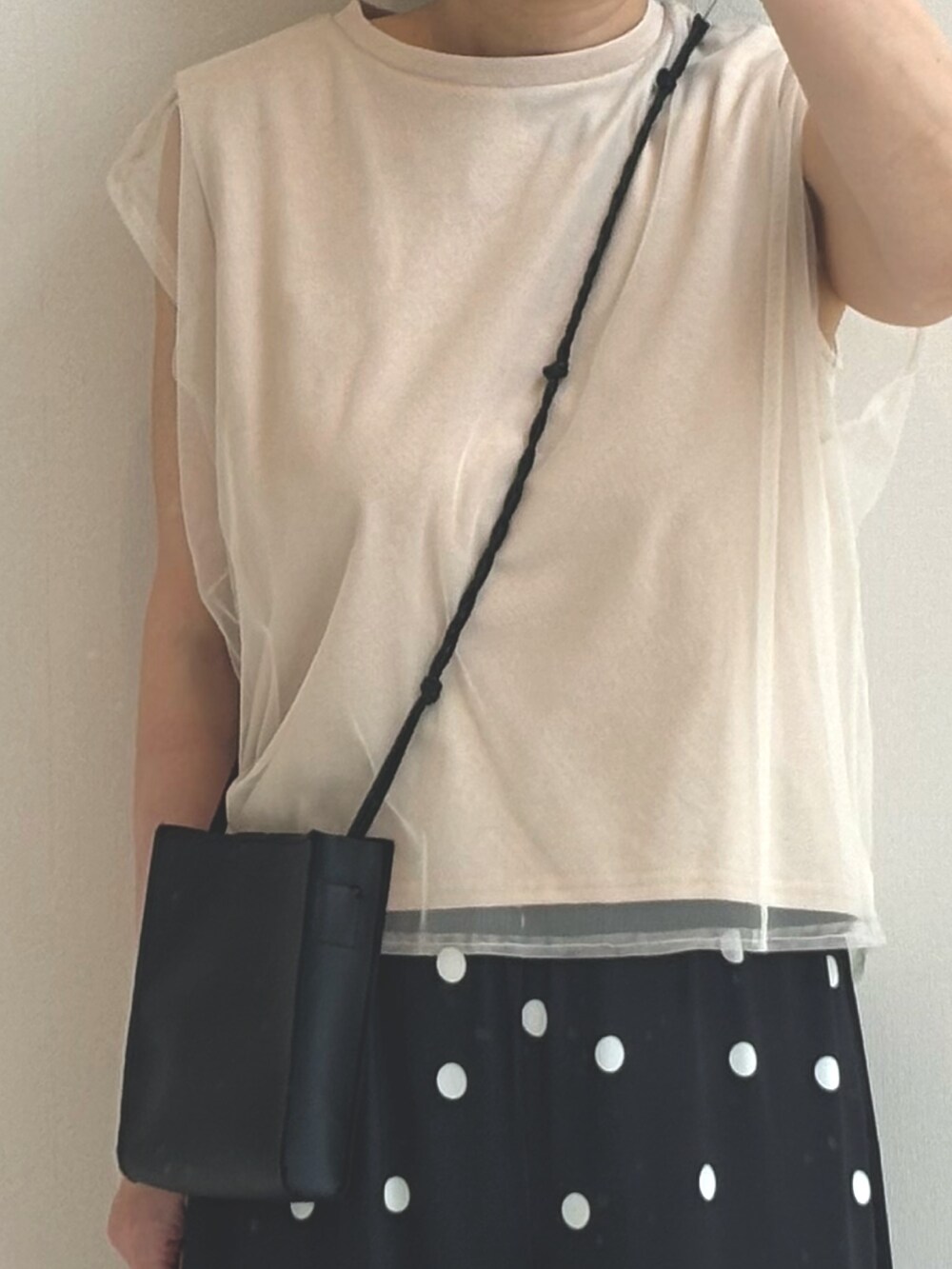 ベージュ系のTシャツ/カットソー、ブラック系のパンツを着用したレディースの春コーディネートの2枚目の写真