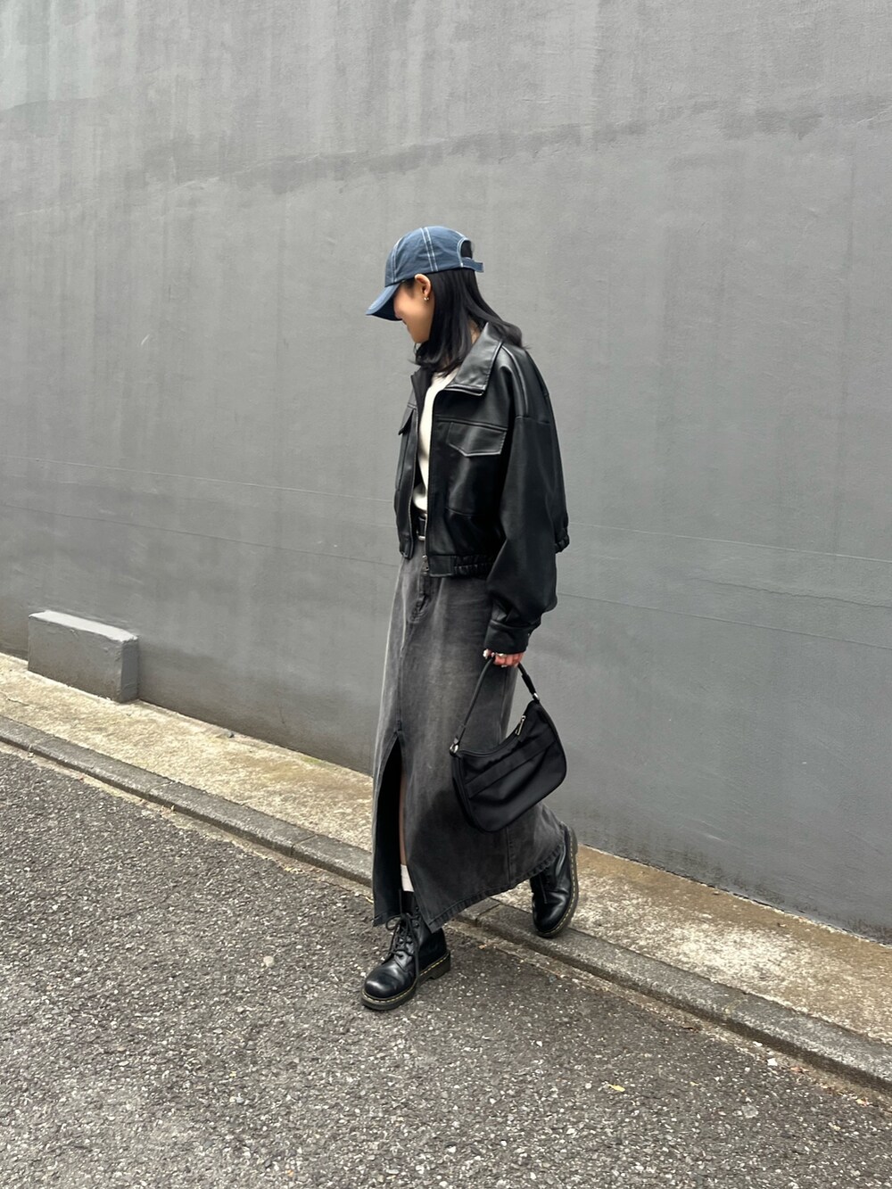 ブラック系のハンドバッグ、ブラック系のデニムスカート、ブラック系のライダースジャケットを着用したレディースの春コーディネートの2枚目の写真