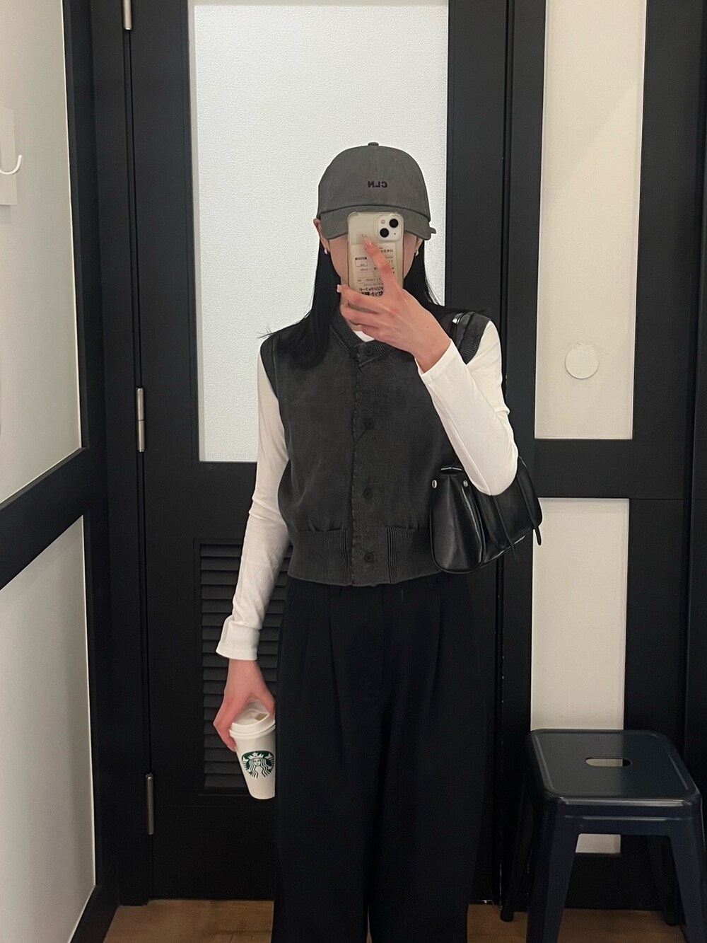 ブラック系のチノパンツ、グレー系のベスト、ホワイト系のTシャツ/カットソーを着用したレディースの春コーディネートの2枚目の写真