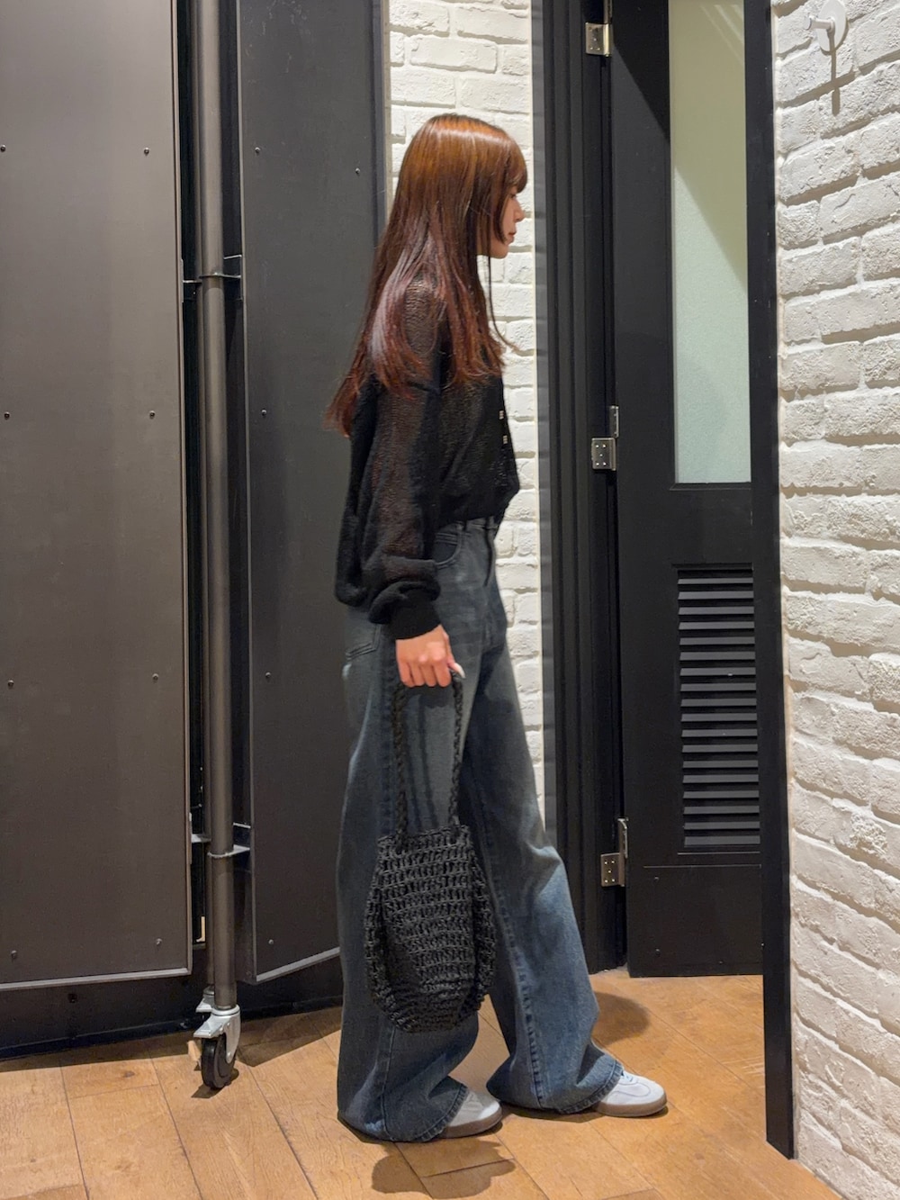 ブルー系のデニムパンツ、ブラック系のかごバッグ、ホワイト系のキャミソールを着用したレディースの夏コーディネートの3枚目の写真