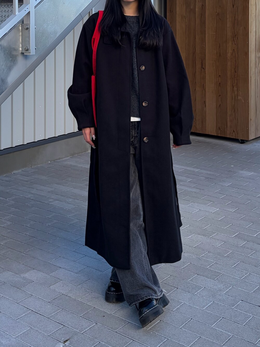 ブラック系のデニムパンツ、ブラック系のステンカラーコート、グレー系のニット/セーターを着用したレディースの冬コーディネートの4枚目の写真