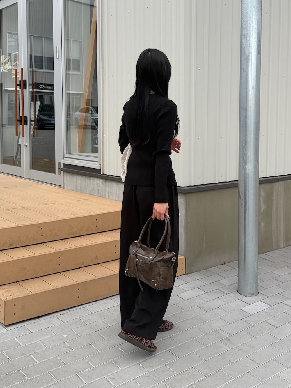 ブラウン系のショルダーバッグ、ブラック系のカーディガン/ボレロ、ブラック系のスラックスを着用したレディースの春コーディネートの2枚目の写真