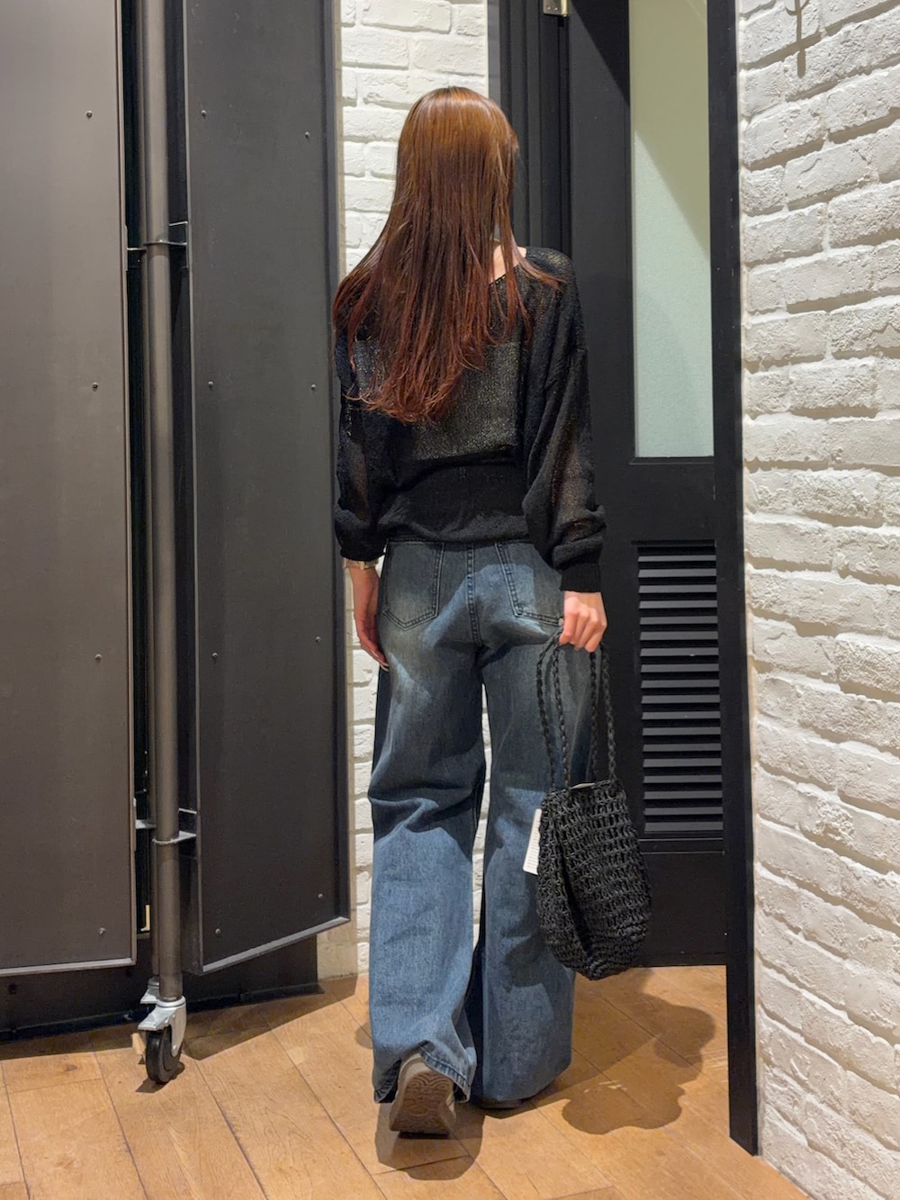 ブルー系のデニムパンツ、ブラック系のかごバッグ、ホワイト系のキャミソールを着用したレディースの夏コーディネートの2枚目の写真