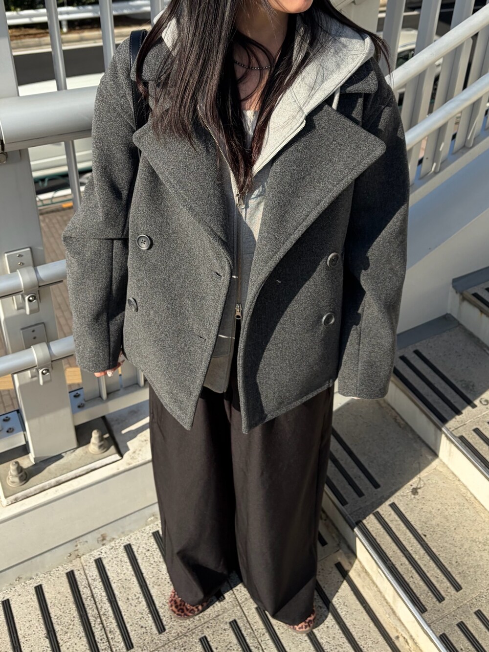 ブラック系のスラックス、グレー系のピーコート、グレー系のパーカーを着用したレディースの冬コーディネートの2枚目の写真