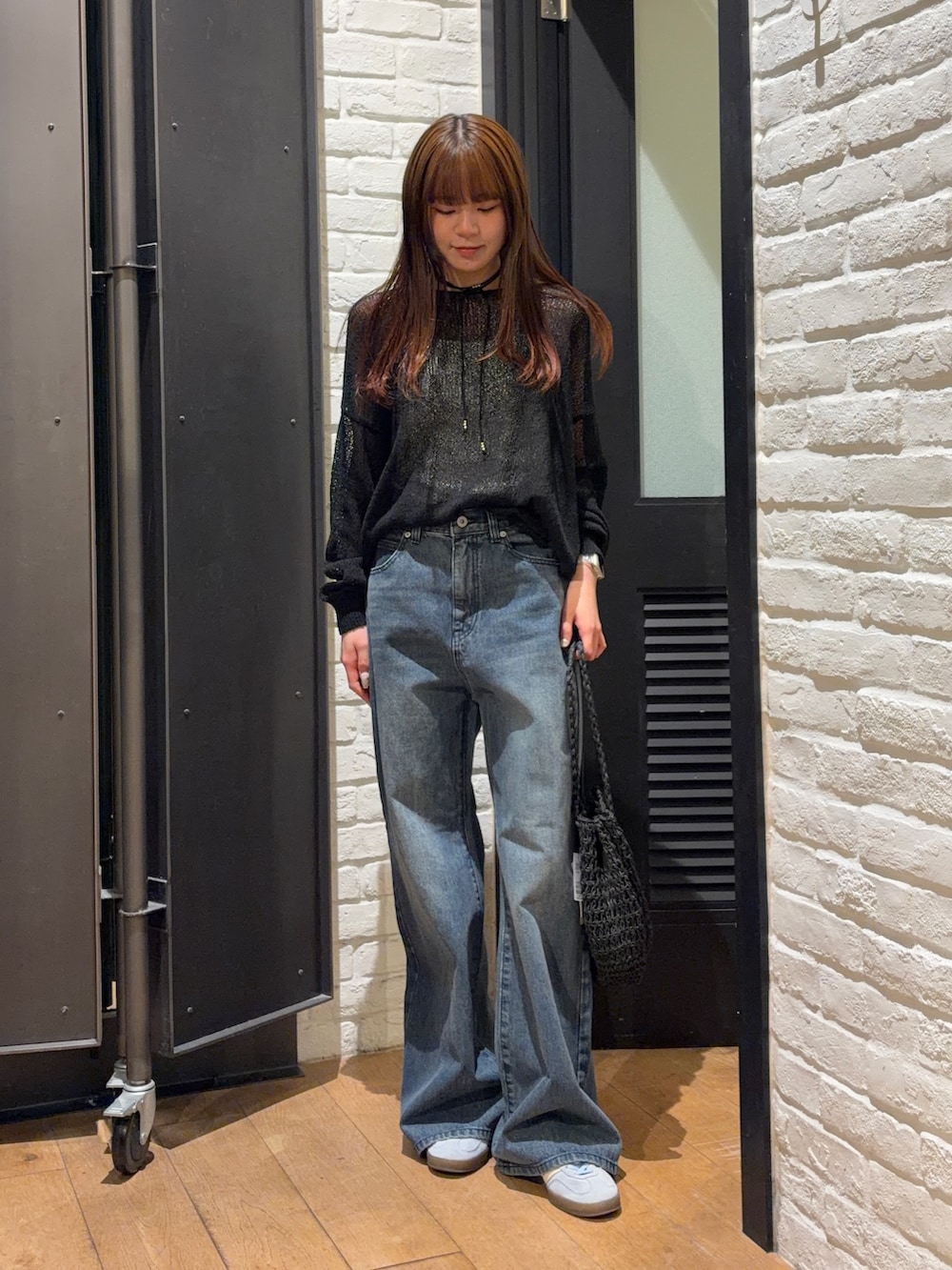 ブルー系のデニムパンツ、ブラック系のかごバッグ、ホワイト系のキャミソールを着用したレディースの夏コーディネートの5枚目の写真
