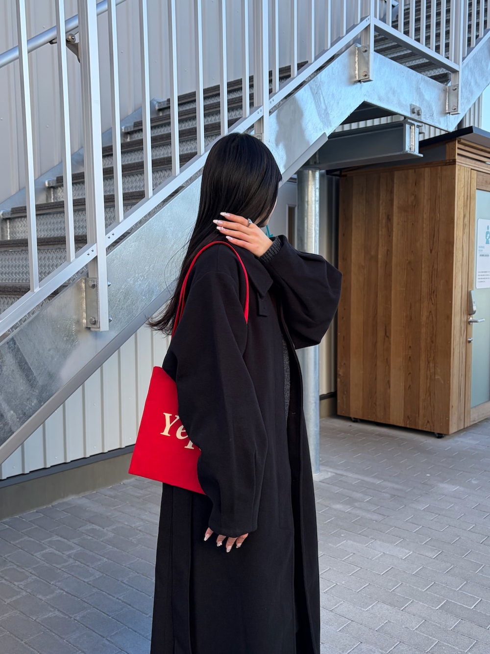 ブラック系のデニムパンツ、ブラック系のステンカラーコート、グレー系のニット/セーターを着用したレディースの冬コーディネートの2枚目の写真