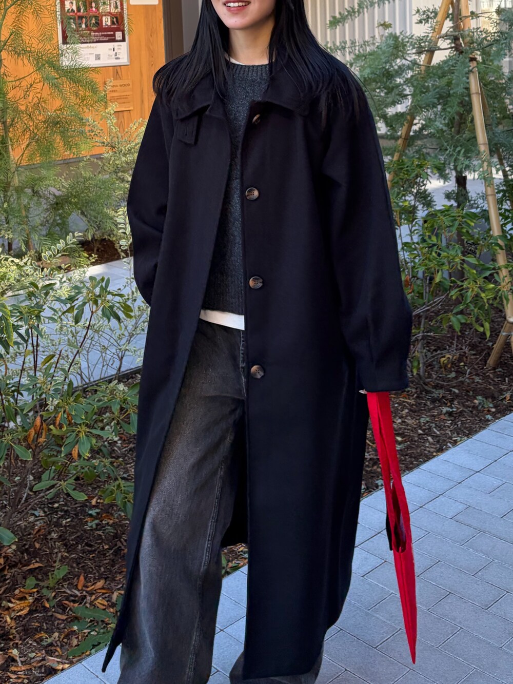 ブラック系のデニムパンツ、ブラック系のステンカラーコート、グレー系のニット/セーターを着用したレディースの冬コーディネートの3枚目の写真