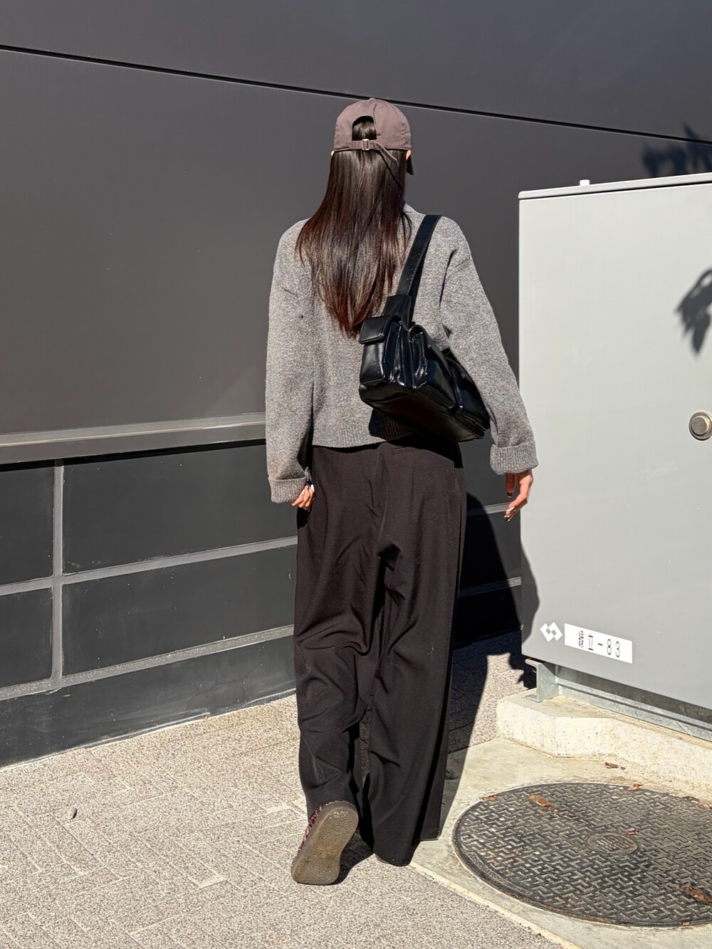 ブラック系のスラックス、ブラック系のショルダーバッグ、ホワイト系のTシャツ/カットソーを着用したレディースの冬コーディネートの3枚目の写真