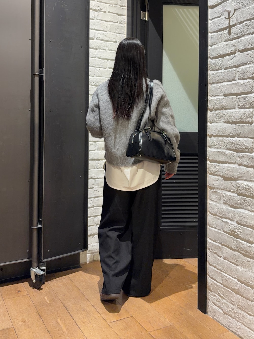 ブラック系のスラックス、ホワイト系のTシャツ/カットソー、グレー系のニット/セーターを着用したレディースの冬コーディネートの3枚目の写真
