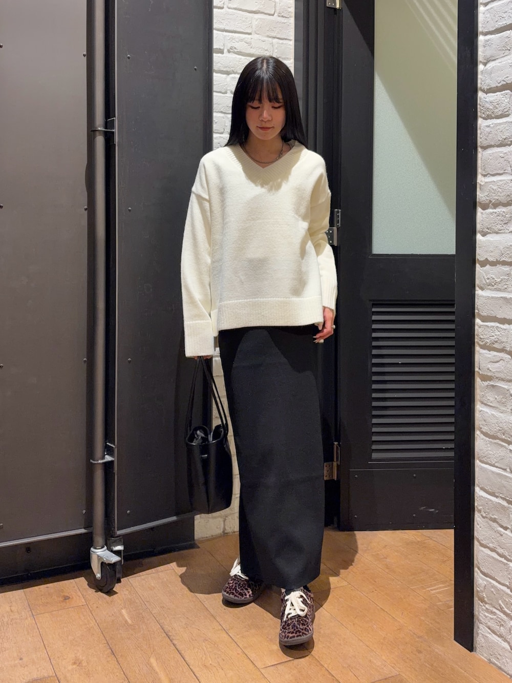 ホワイト系のニット/セーター、ブラック系のスカート、ブラック系のショルダーバッグを着用したレディースの冬コーディネートの3枚目の写真