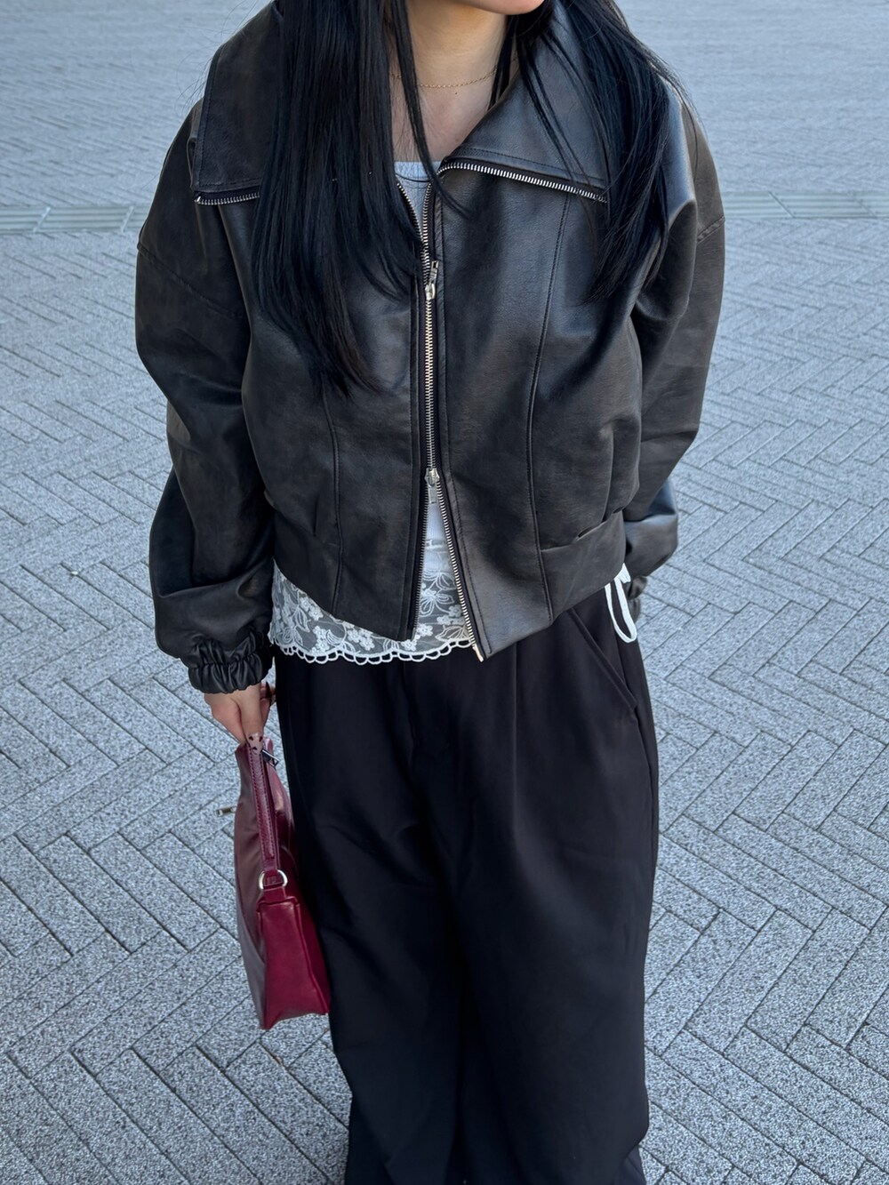 レッド系のハンドバッグ、ブラック系のスラックス、ホワイト系のTシャツ/カットソーを着用したレディースの冬コーディネートの2枚目の写真