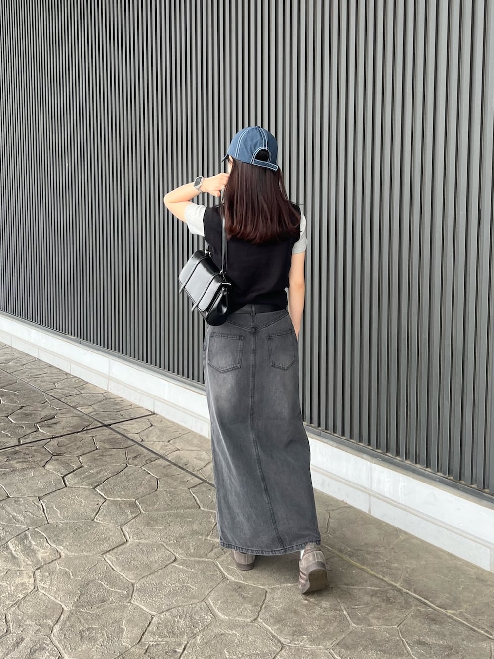 ブラック系のベスト、グレー系のTシャツ/カットソー、ブラック系のハンドバッグを着用したレディースの春コーディネートの2枚目の写真