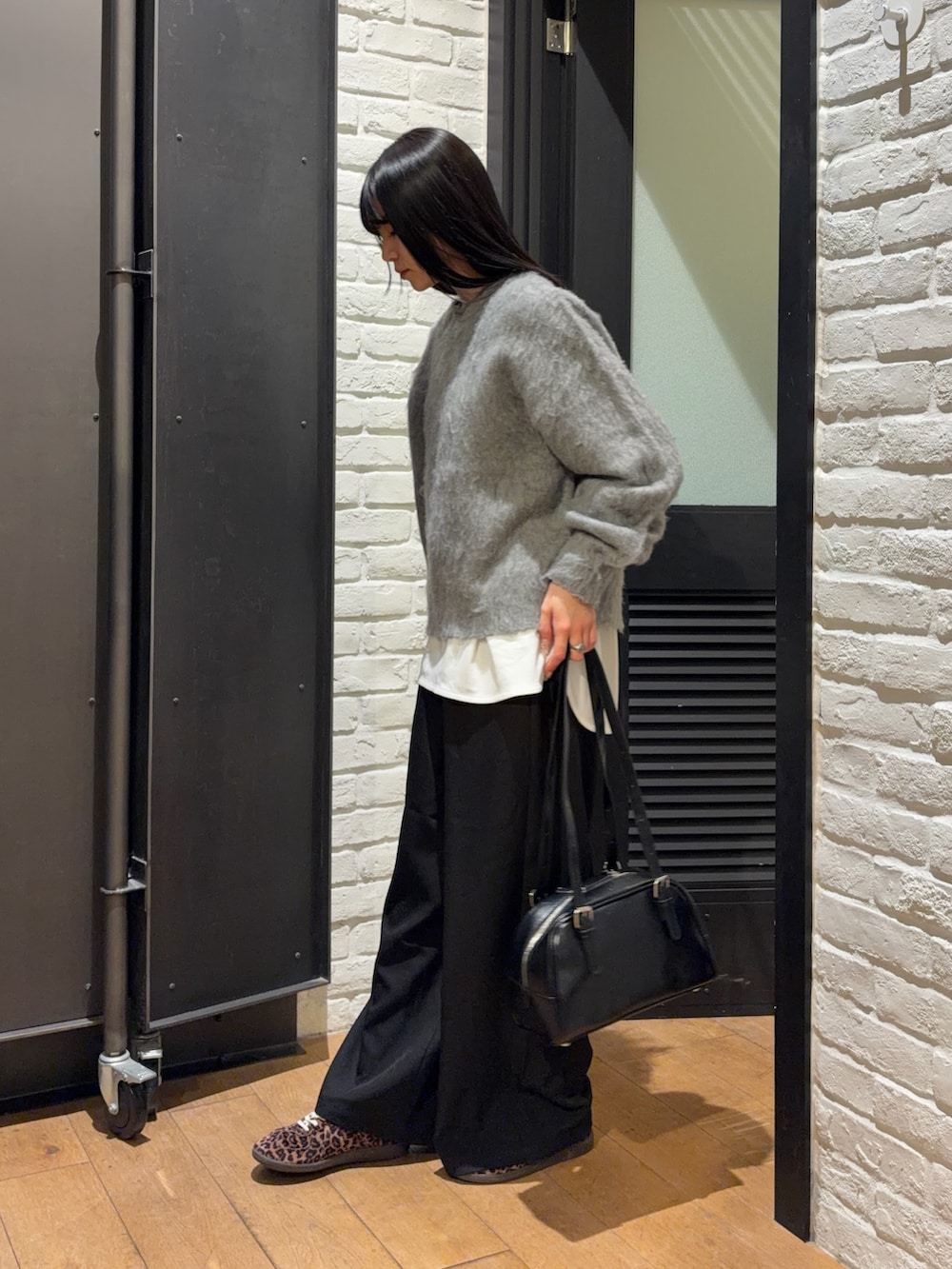 ブラック系のスラックス、ホワイト系のTシャツ/カットソー、グレー系のニット/セーターを着用したレディースの冬コーディネートの4枚目の写真
