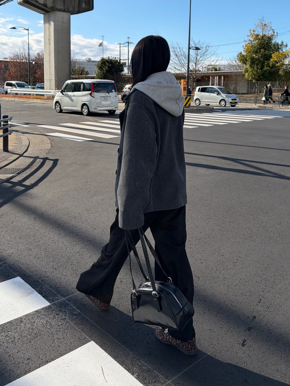 ブラック系のスラックス、グレー系のピーコート、グレー系のパーカーを着用したレディースの冬コーディネートの4枚目の写真