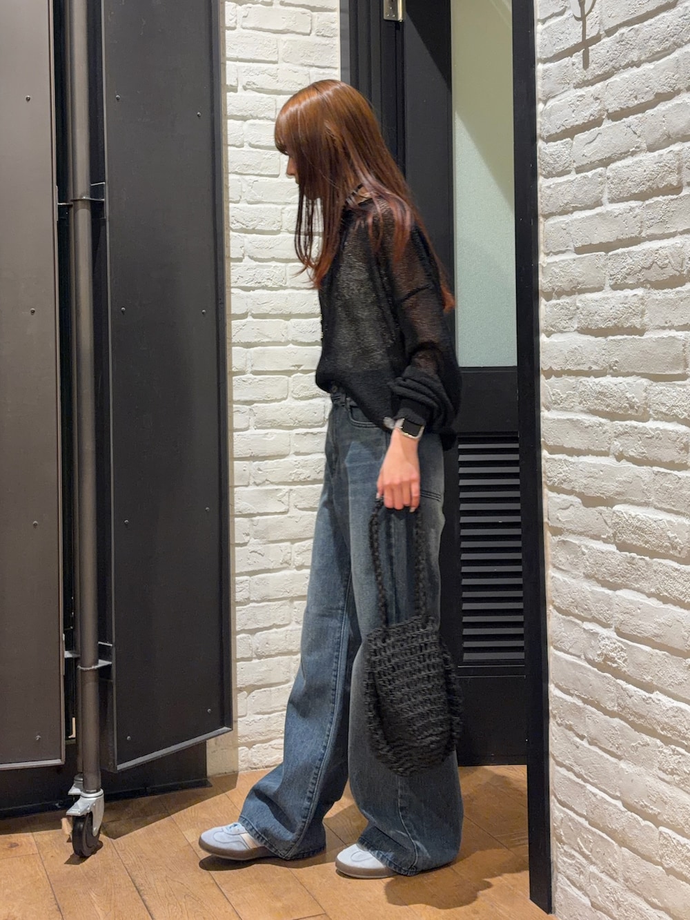ブルー系のデニムパンツ、ブラック系のかごバッグ、ホワイト系のキャミソールを着用したレディースの夏コーディネートの4枚目の写真