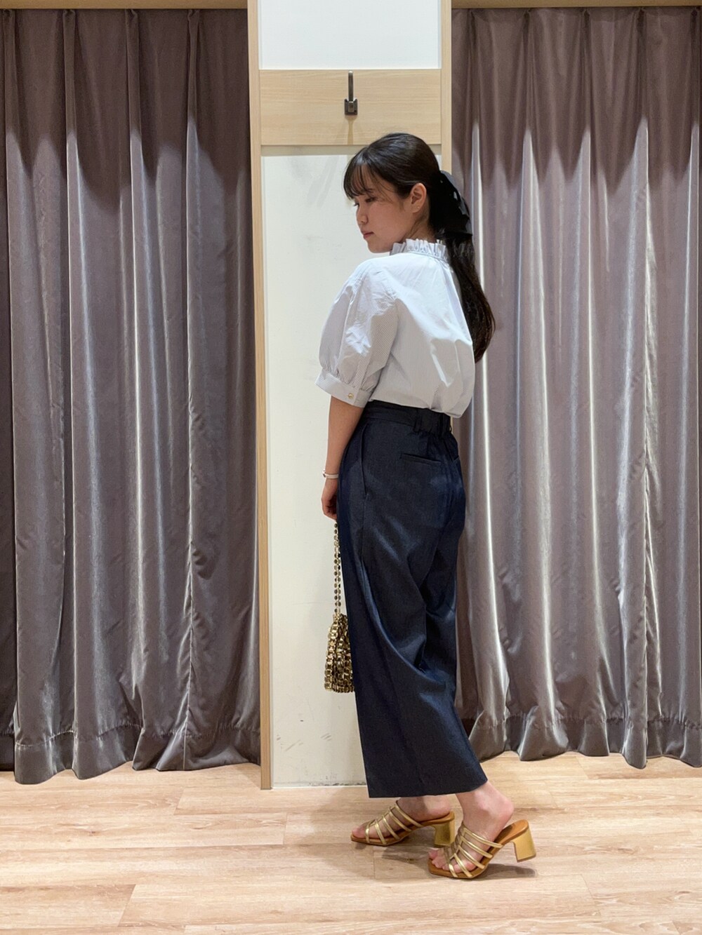 ブルー系のシャツ/ブラウス、ゴールド系のハンドバッグ、ゴールド系のサンダルを着用したレディースの春コーディネートの2枚目の写真