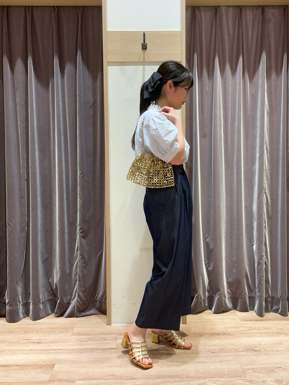 ブルー系のシャツ/ブラウス、ゴールド系のハンドバッグ、ゴールド系のサンダルを着用したレディースの春コーディネートの3枚目の写真