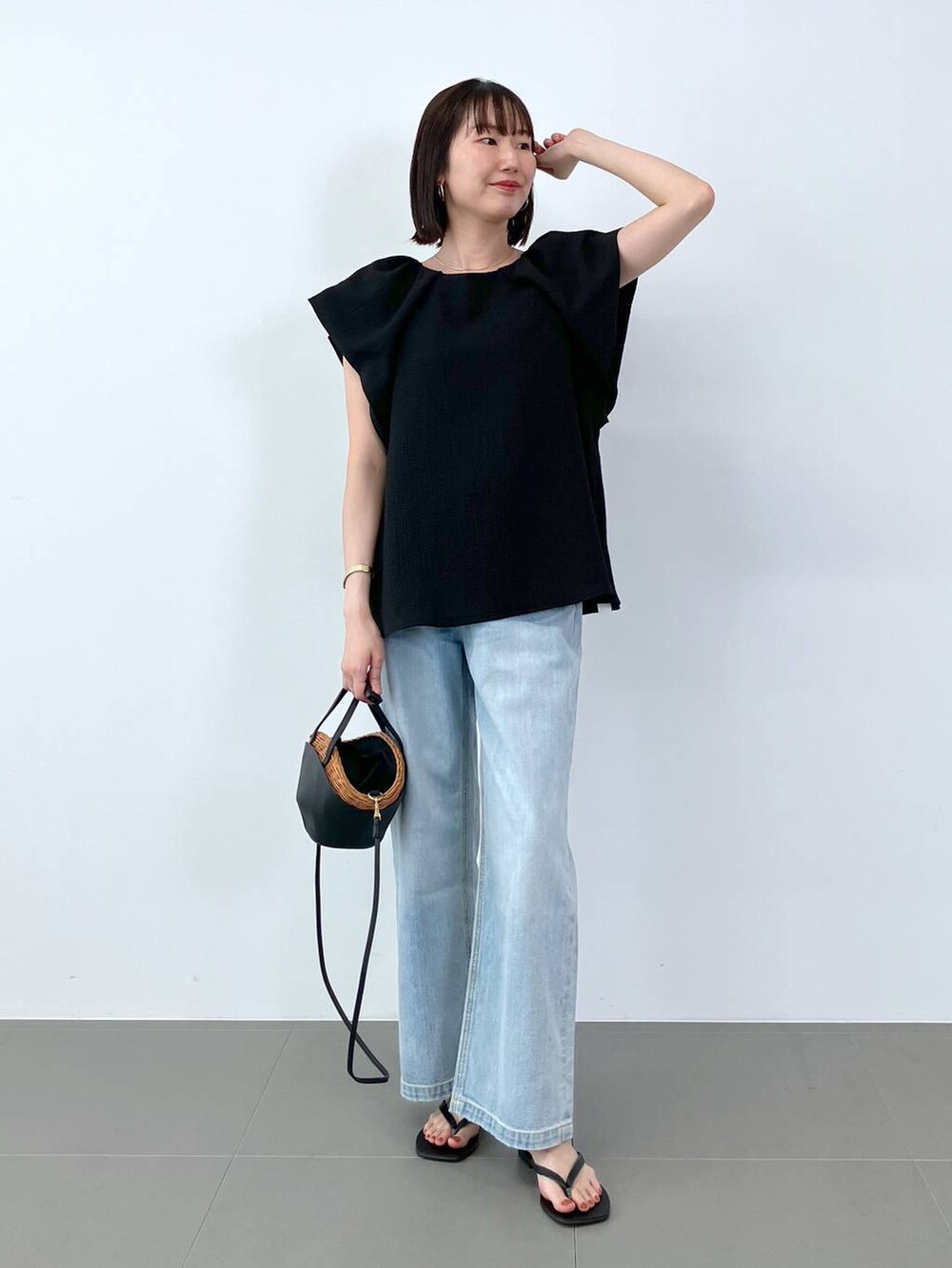 ブラック系のシャツ/ブラウス、ブラック系のかごバッグ、ブルー系のデニムパンツを着用したレディースの夏コーディネートの4枚目の写真