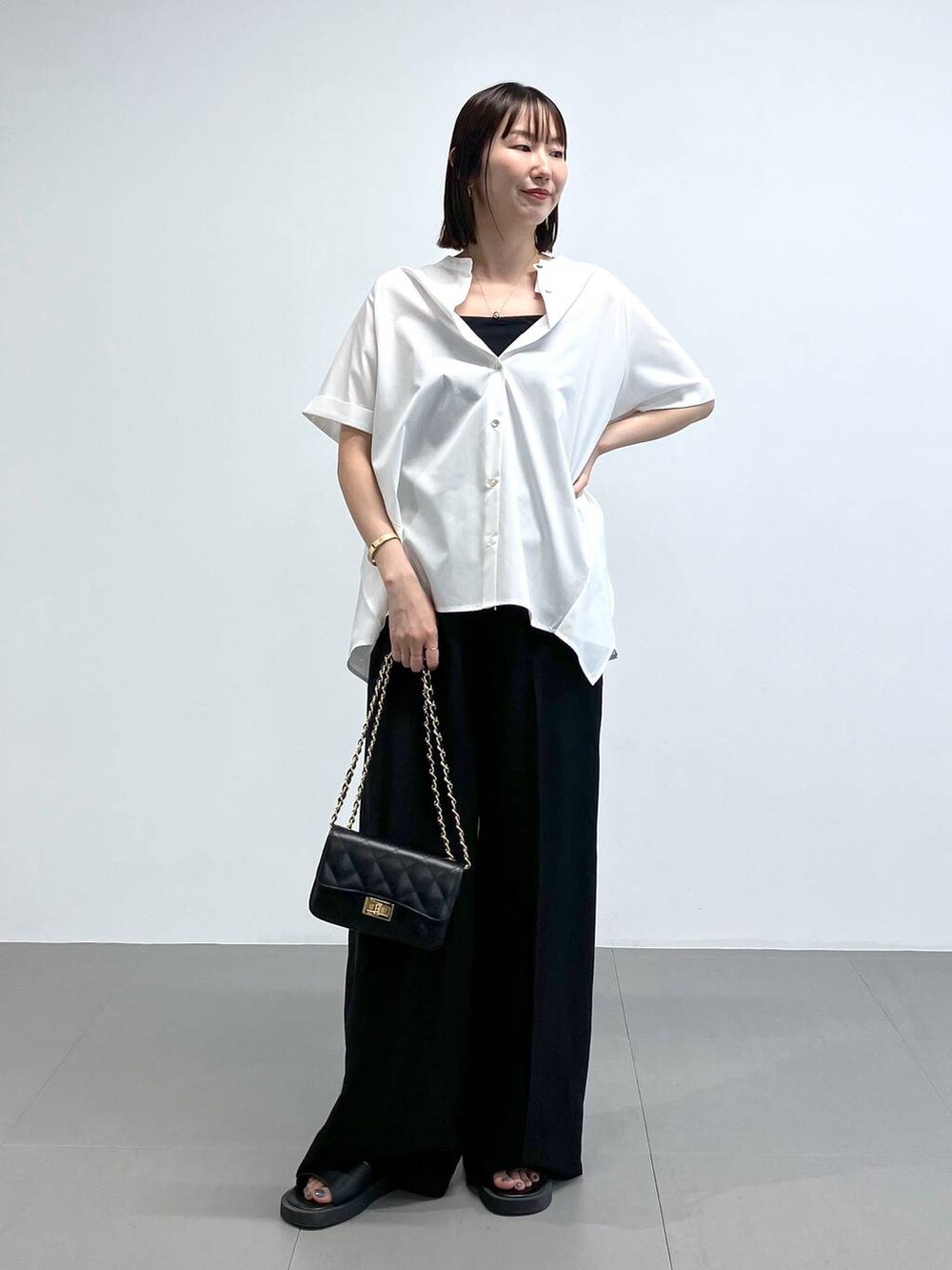 ブラック系のショルダーバッグ、ブラック系のその他パンツ、ホワイト系のシャツ/ブラウスを着用したレディースの夏コーディネートの4枚目の写真