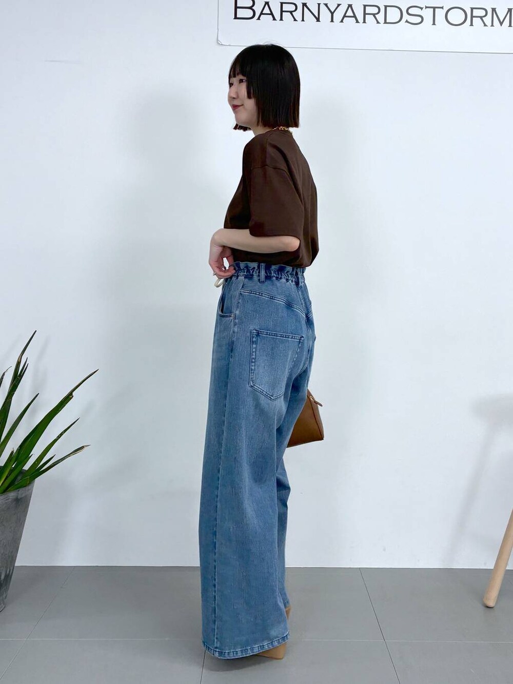 ブラウン系のボストンバッグ、ブルー系のデニムパンツ、ブラウン系のTシャツ/カットソーを着用したレディースの春コーディネートの4枚目の写真