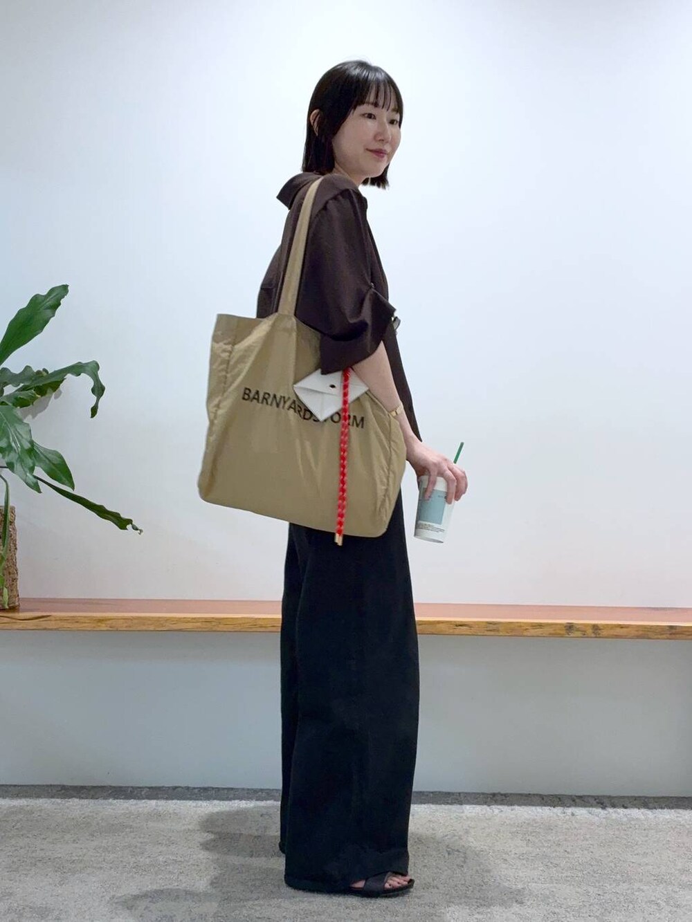 ブラック系のデニムパンツ、ベージュ系のトートバッグ、ブラウン系のシャツ/ブラウスを着用したレディースの春コーディネートの2枚目の写真