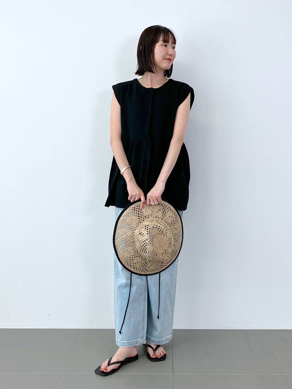 ブルー系のデニムパンツ、ブラック系のサンダル、ブラック系のベストを着用したレディースの夏コーディネートの2枚目の写真