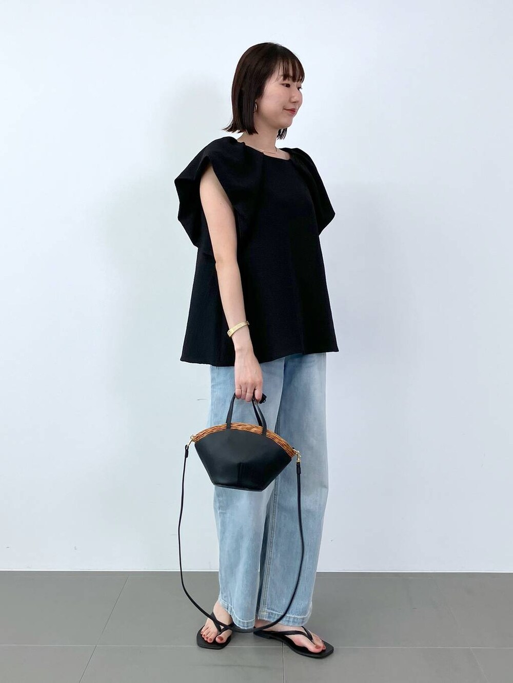 ブラック系のシャツ/ブラウス、ブラック系のかごバッグ、ブルー系のデニムパンツを着用したレディースの夏コーディネートの3枚目の写真