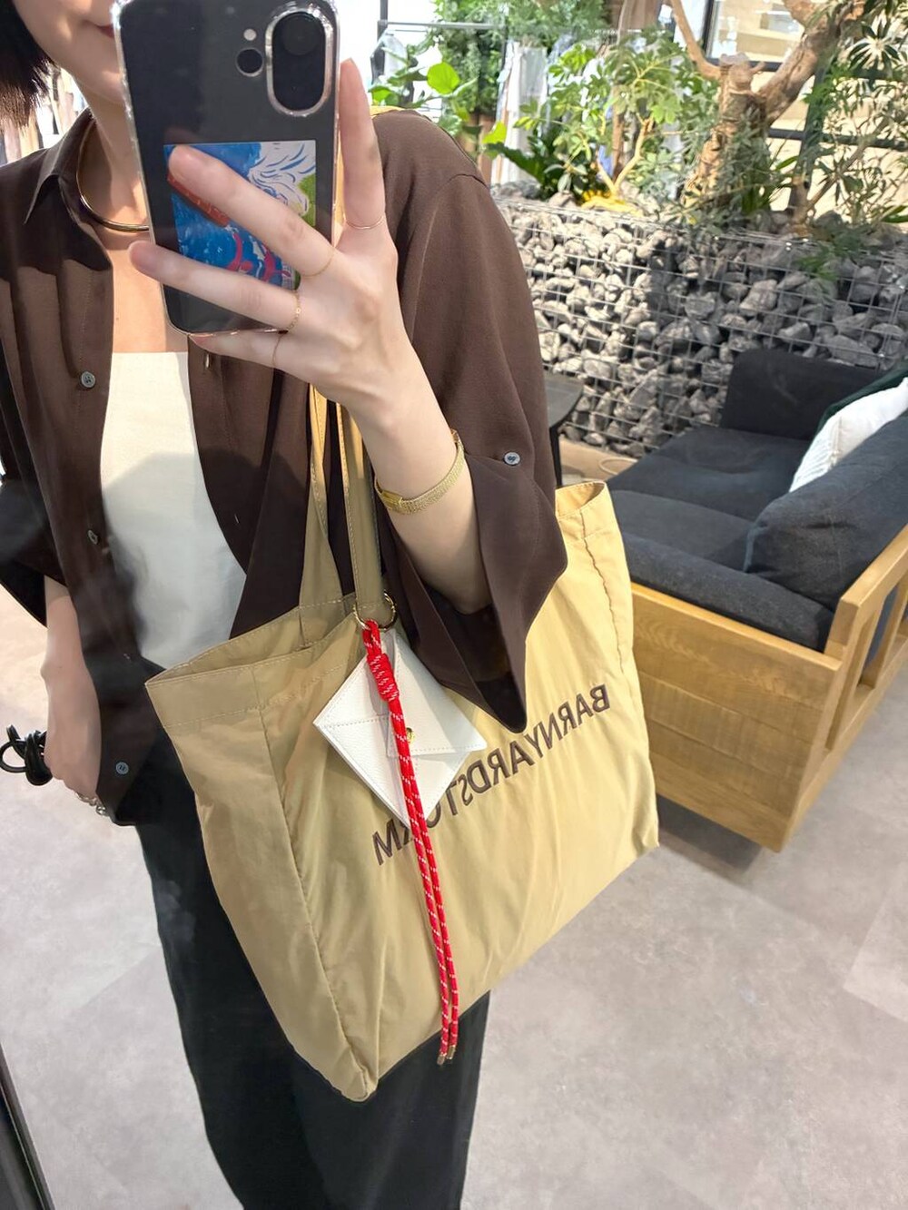 ブラック系のデニムパンツ、ベージュ系のトートバッグ、ブラウン系のシャツ/ブラウスを着用したレディースの春コーディネートの5枚目の写真