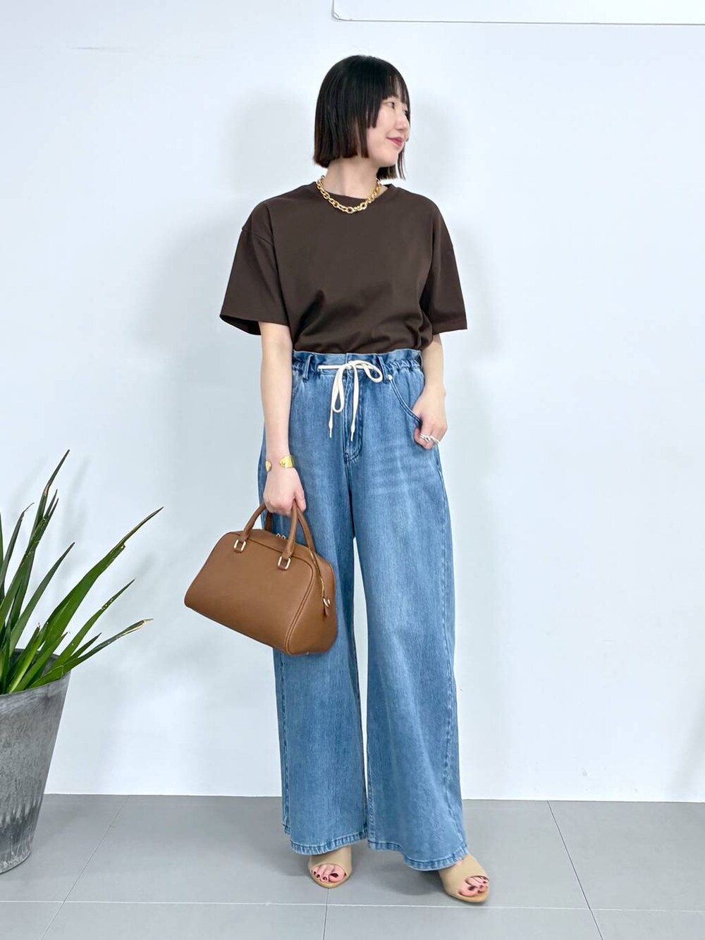 ブラウン系のボストンバッグ、ブルー系のデニムパンツ、ブラウン系のTシャツ/カットソーを着用したレディースの春コーディネートの2枚目の写真