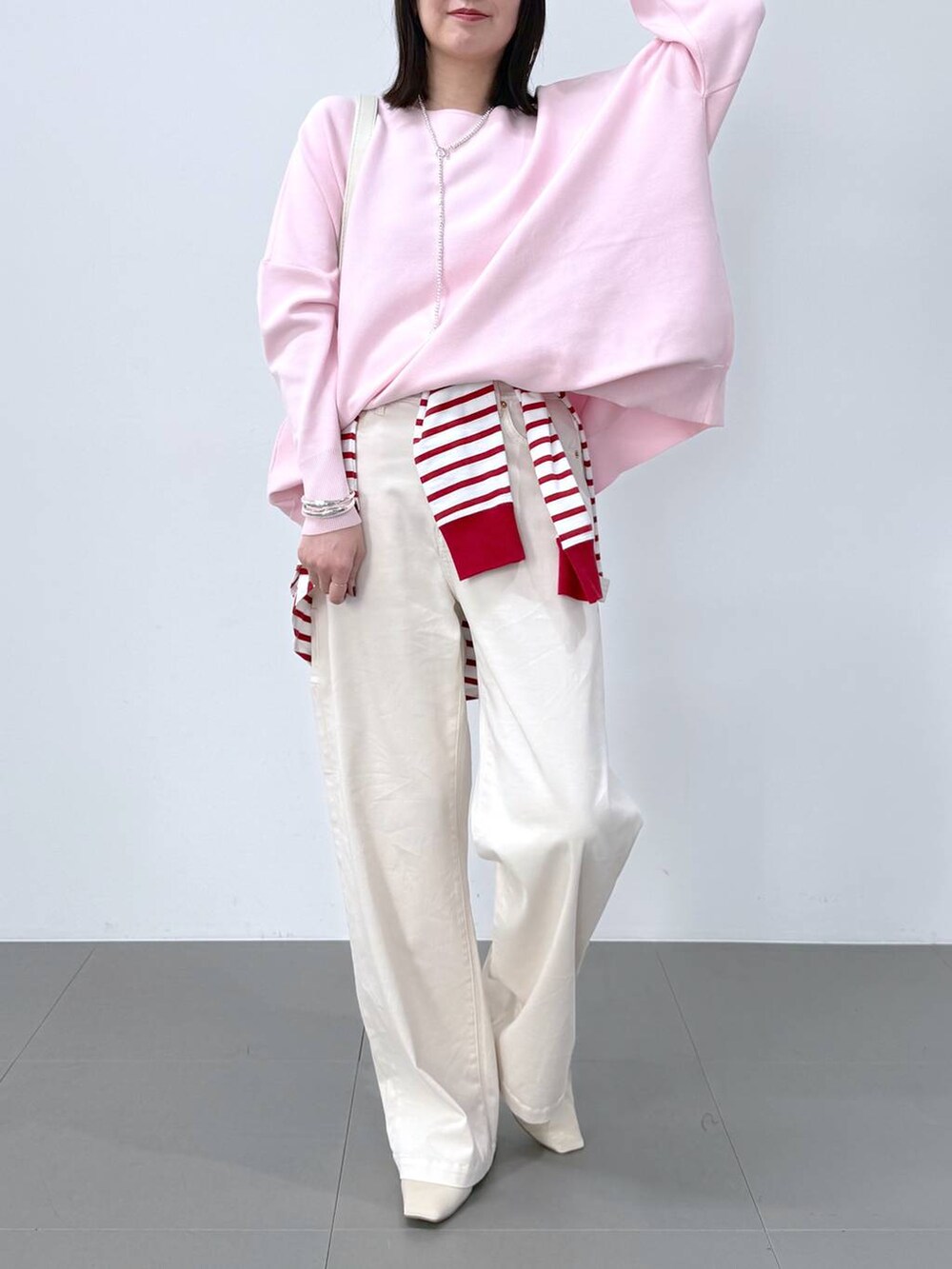 レッド系のTシャツ/カットソー、ホワイト系のショルダーバッグ、ピンク系のニット/セーターを着用したレディースの冬コーディネートの2枚目の写真